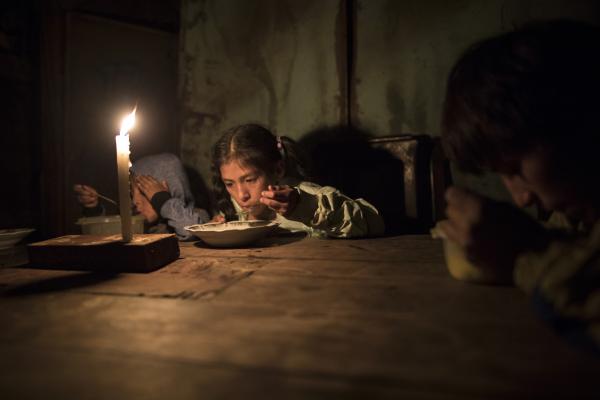 Λίμα, Περού, 8 Ιουνίου 2020: Τρία αδέλφια δειπνούν υπό το φως κεριού στο σπίτι τους στη γειτονιά Nueva Esperanza, που είναι αποκομμένη από το δίκτυο ηλεκτρικού ρεύματος. 