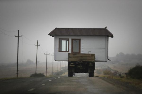 Ναγκόρνο Καραμπάχ, 18 Νοεμβρίου 2020: Οικογένεια οδηγεί φορτηγό που μεταφέρει ένα μικρό σπίτι σε λεωφόρο, καθώς φεύγουν από την περιοχή του Ναγκόρνο Καραμπάχ, λίγο πριν από την απόφαση για κατάπαυση του πυρός. Η συμφωνία Αρμενίας-Αζερμπαϊτζάν προέβλεπε την παραχώρηση αρμενικών εδαφών στους Αζέρους και έτσι πολλοί Αρμένιοι αναγκάστηκαν να εγκαταλείψουν τις εστίες τους. 